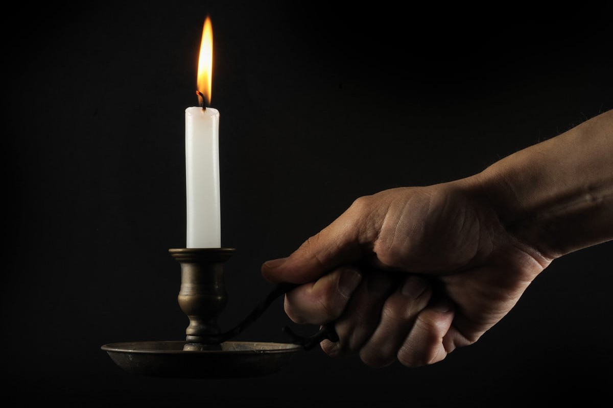 Person holding a candle stick in a holder